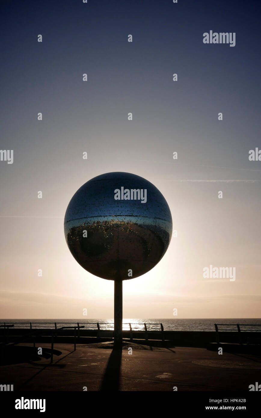Sun setting behind the giant mirror ball on Blackpool promenade Stock