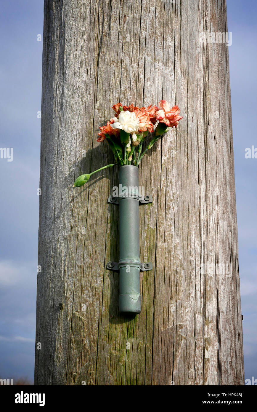 Floral tribute attached to wooden post Stock Photo