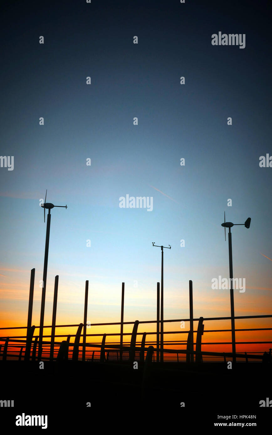 Wind turbines at dusk silhouetted against sunset Stock Photo