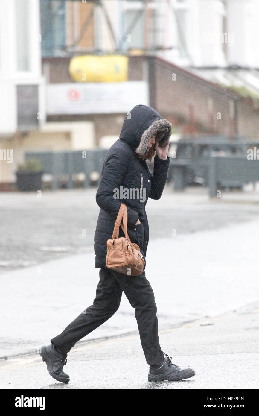 Female commuter walking to work in wet and windy weather as a result of Storm Doris as it hit Llandudno, North Wales Stock Photo