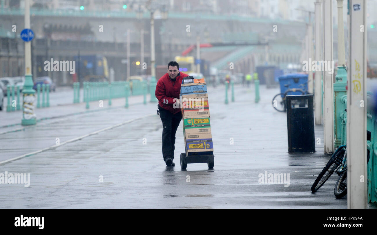 Brighton, UK. 23rd Feb, 2017. A delivery man battles through the wind and rain on Brighton