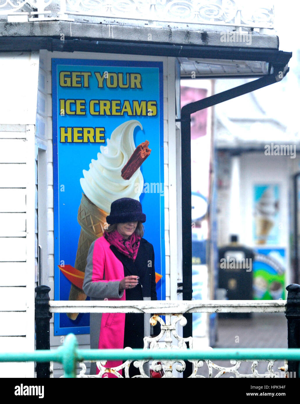 Brighton, UK. 23rd Feb, 2017. A woman shelters from the wind and rain by an ice cream kiosk on Brighton seafront this morning as Storm Doris hits the south coast today. Some parts of Britain are forecast to get winds of up to 70mph Credit: Simon Dack/Alamy Live News Credit: Simon Dack/Alamy Live News Stock Photo