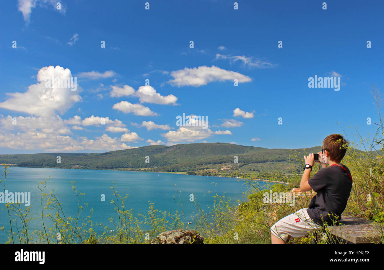 A young man is taking a photo of a landscape of Bracciano lake, near Rome, Italy Stock Photo