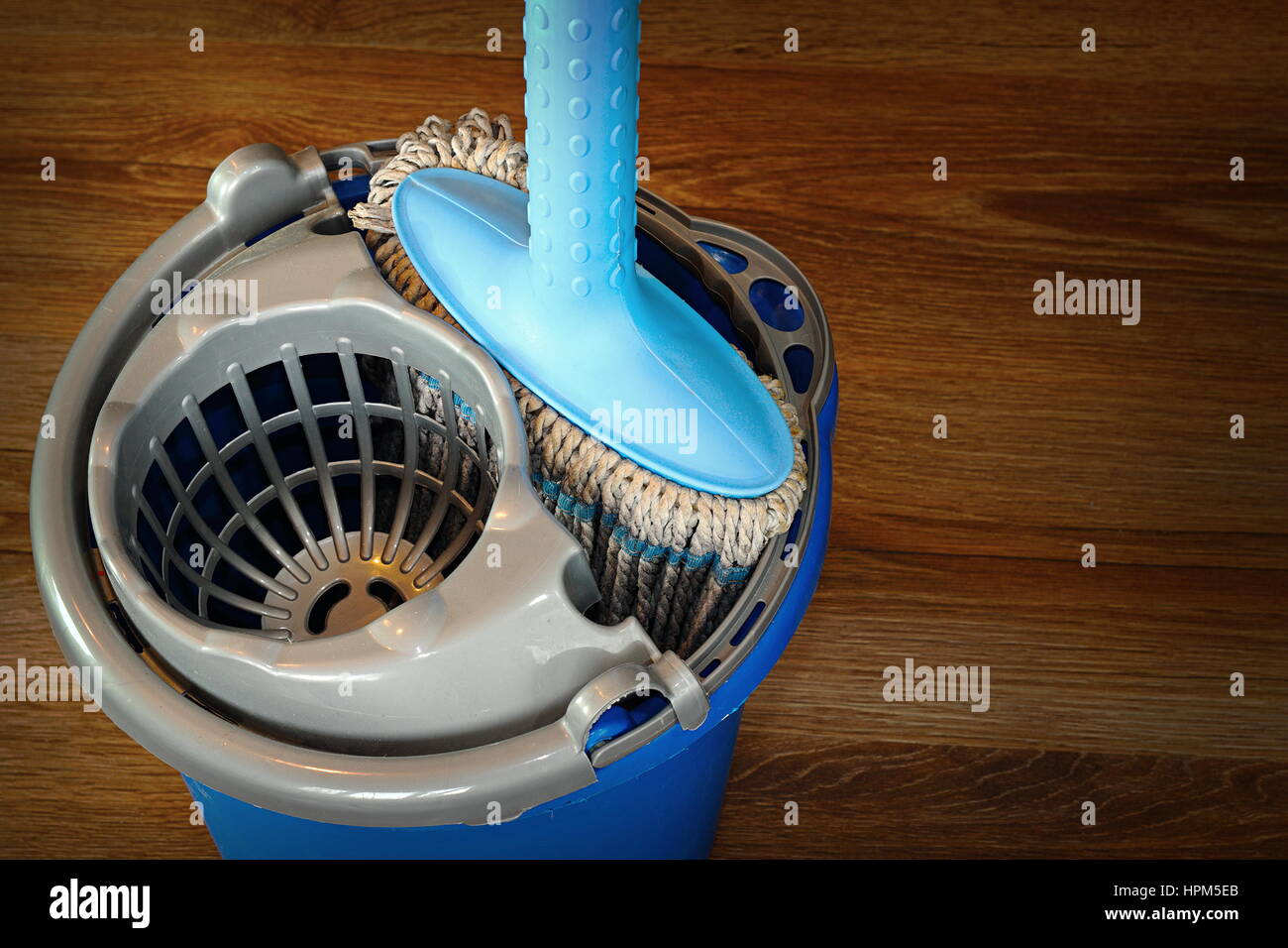 mop and blue bucket ready for cleaning wooden parquet floor Stock Photo