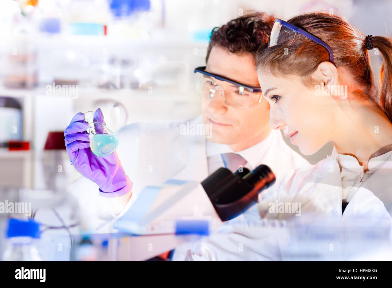 Life science researchers observing blue solution in laboratory. Stock Photo