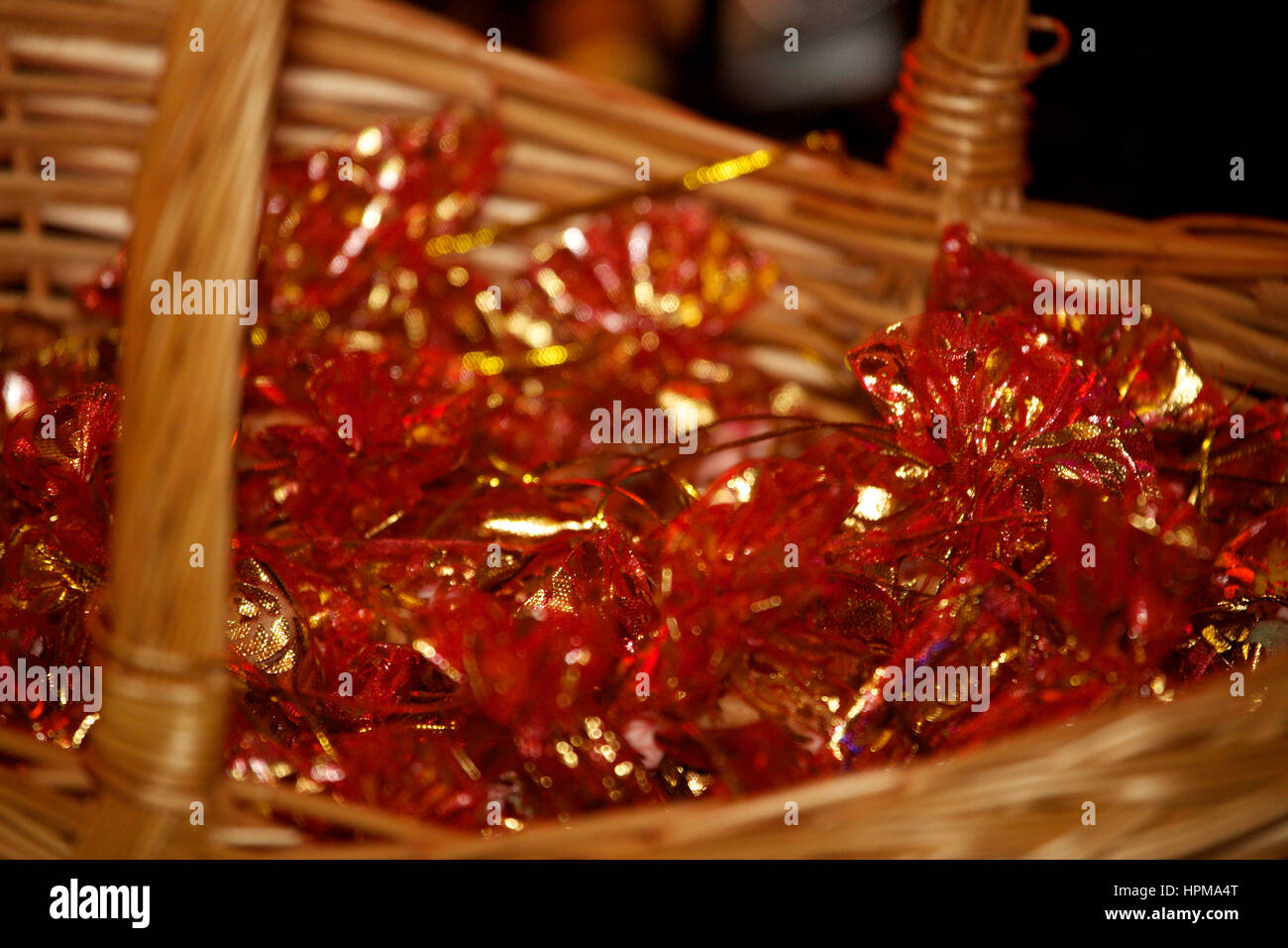 Red gift bags with gold ties in wicker basket Stock Photo