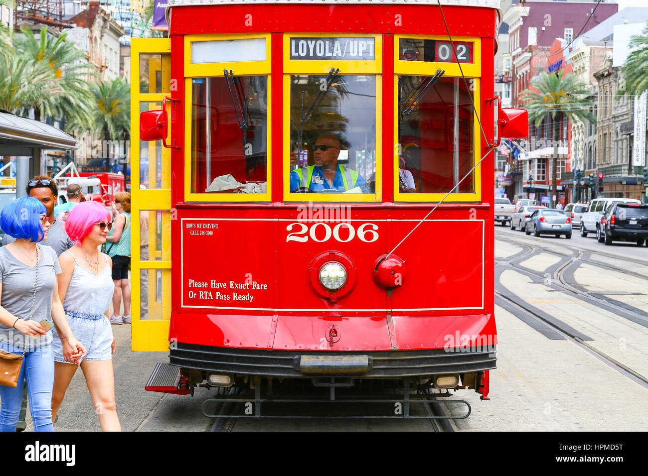 New Orleans, USA - May 14, 2015: Streetcar stopped on Canal Street, two women with colorful wigs crossing the street in front of it. Stock Photo