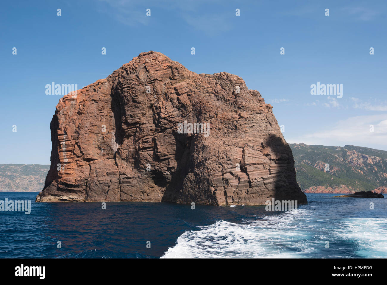 Volcanic red rock emerges from the transparent sea in the natural park Scandola. Stock Photo