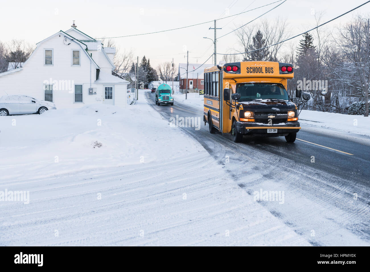 Moose Creek, Canada - January 30, 2017: School bus stopping to let children off after a day at school on a snowy day in a small country town. Stock Photo