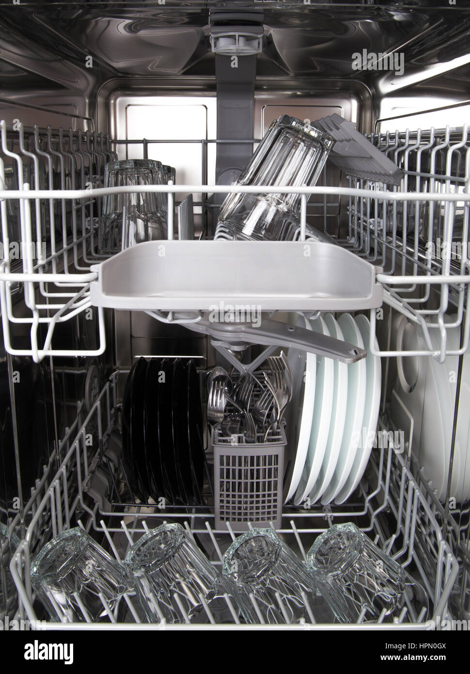 Clean glasses and white plates in modern dishwasher machine Stock Photo