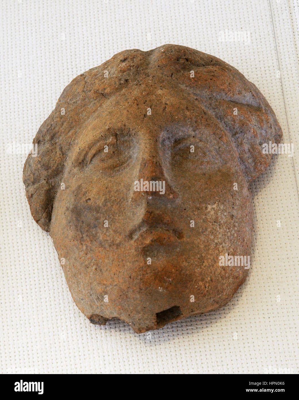 Roman antefix. Vertical block which terminates the covering tiles of the roof. Moulded ceramic. Head of classic. Apparenty feminine with tufts and braids. 1st century BC-1st century BC. Spain. Terracotta. National Archaeological Museum. Tarragona. Catalonia, Spain. Stock Photo