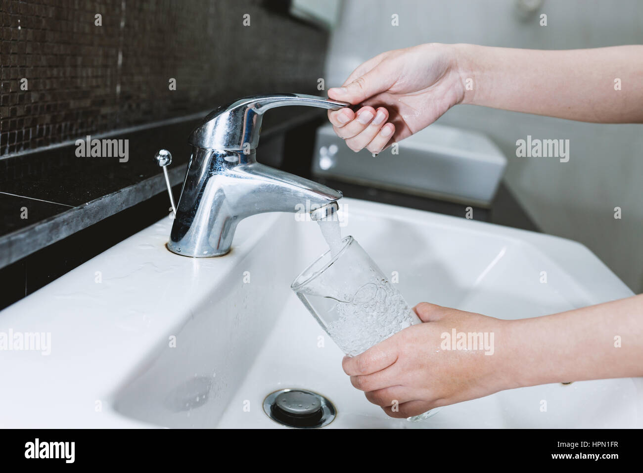 Woman Filling A Glass Of Water From A Stainless Steel Or Chrome
