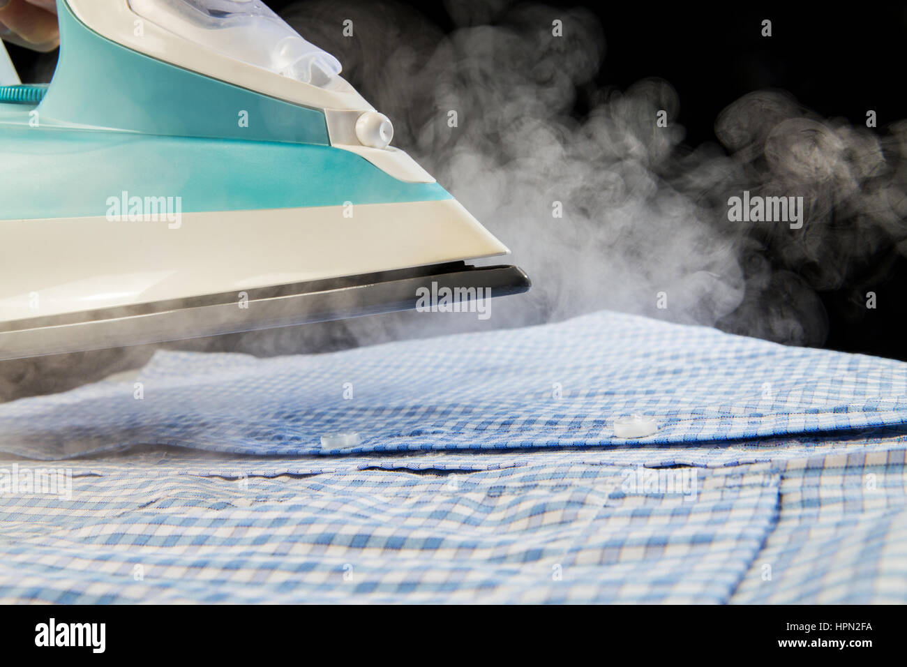Shirt ironing with steam on black background Stock Photo Alamy