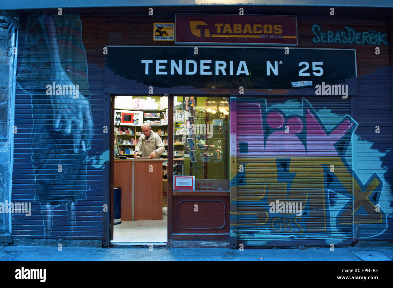 Spain: a tobacconist in his smoke shop after sunset in the center of Casco Viejo, the oldest district and the original nucleus of the city of Bilbao Stock Photo