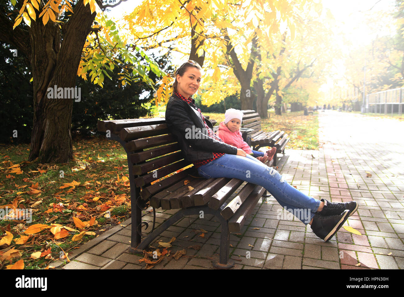 Young women and her daughter sitting on bench in park Stock Photo - Alamy