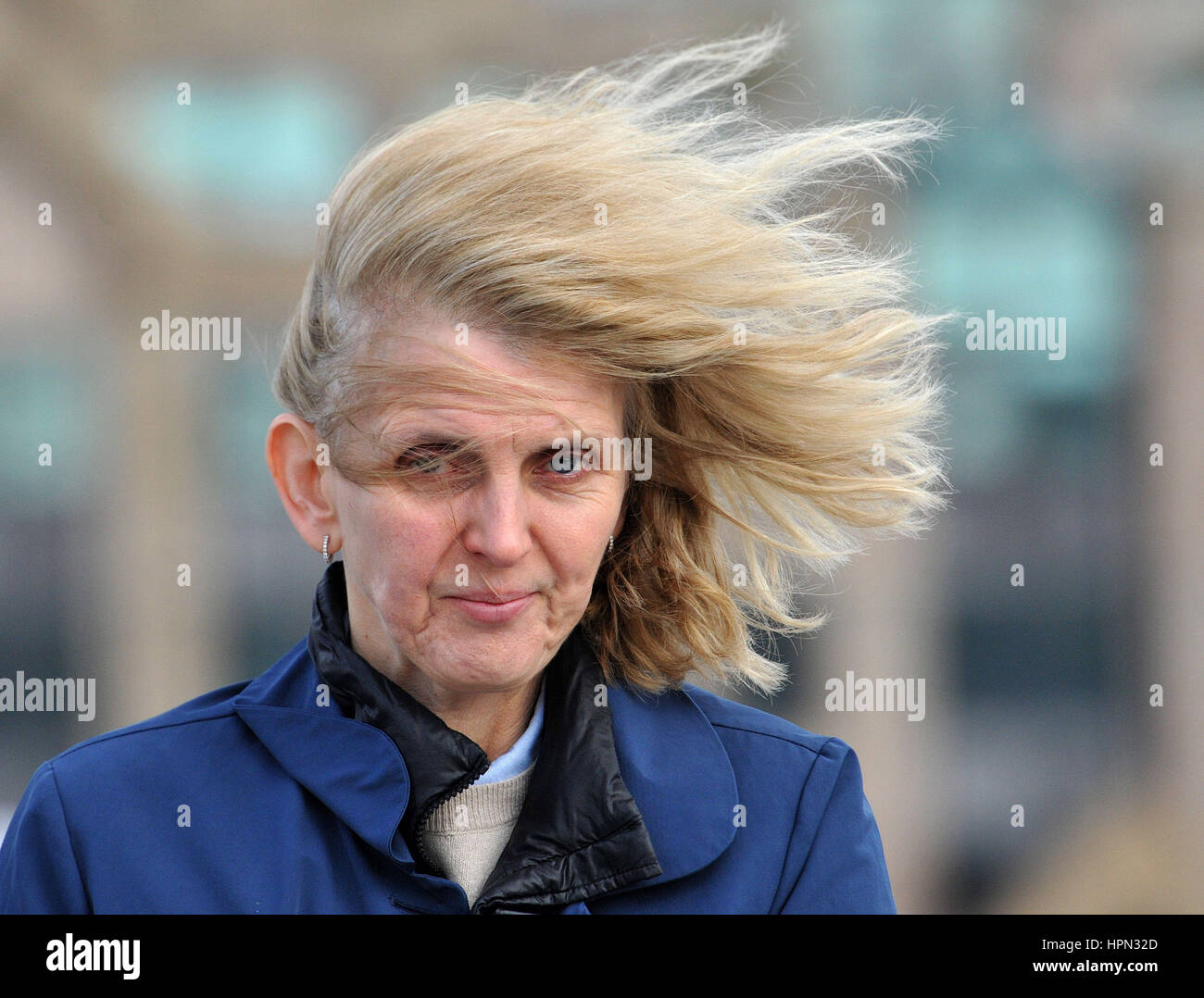 The hair of a woman is caught in a gust of wind as she walks across Millennium Bridge in central London, as flights have been cancelled and commuters were warned they faced delays after Storm Doris reached nearly 90mph on its way to batter Britain. Stock Photo