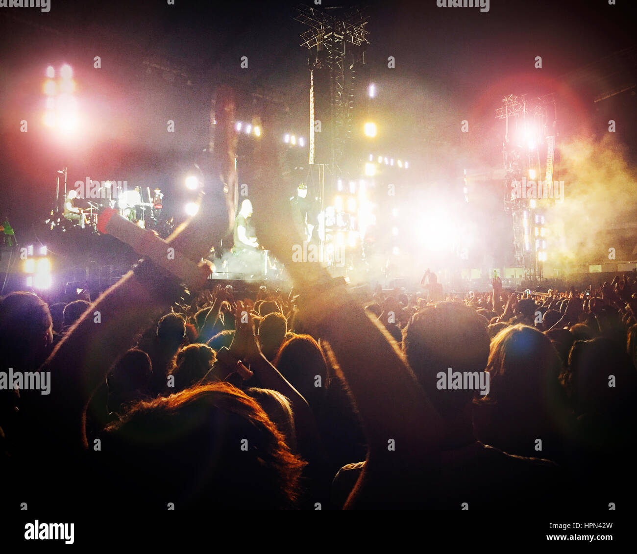 Large crowd at a concert. It is dark and there are colourful lights. Stock Photo