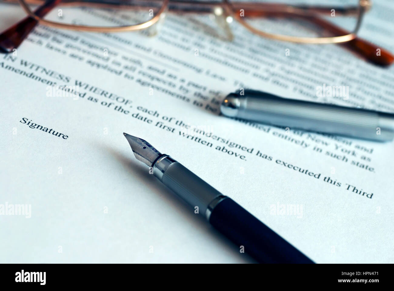 close-up of a fountain pen and eyeglasses over a business contract to ...