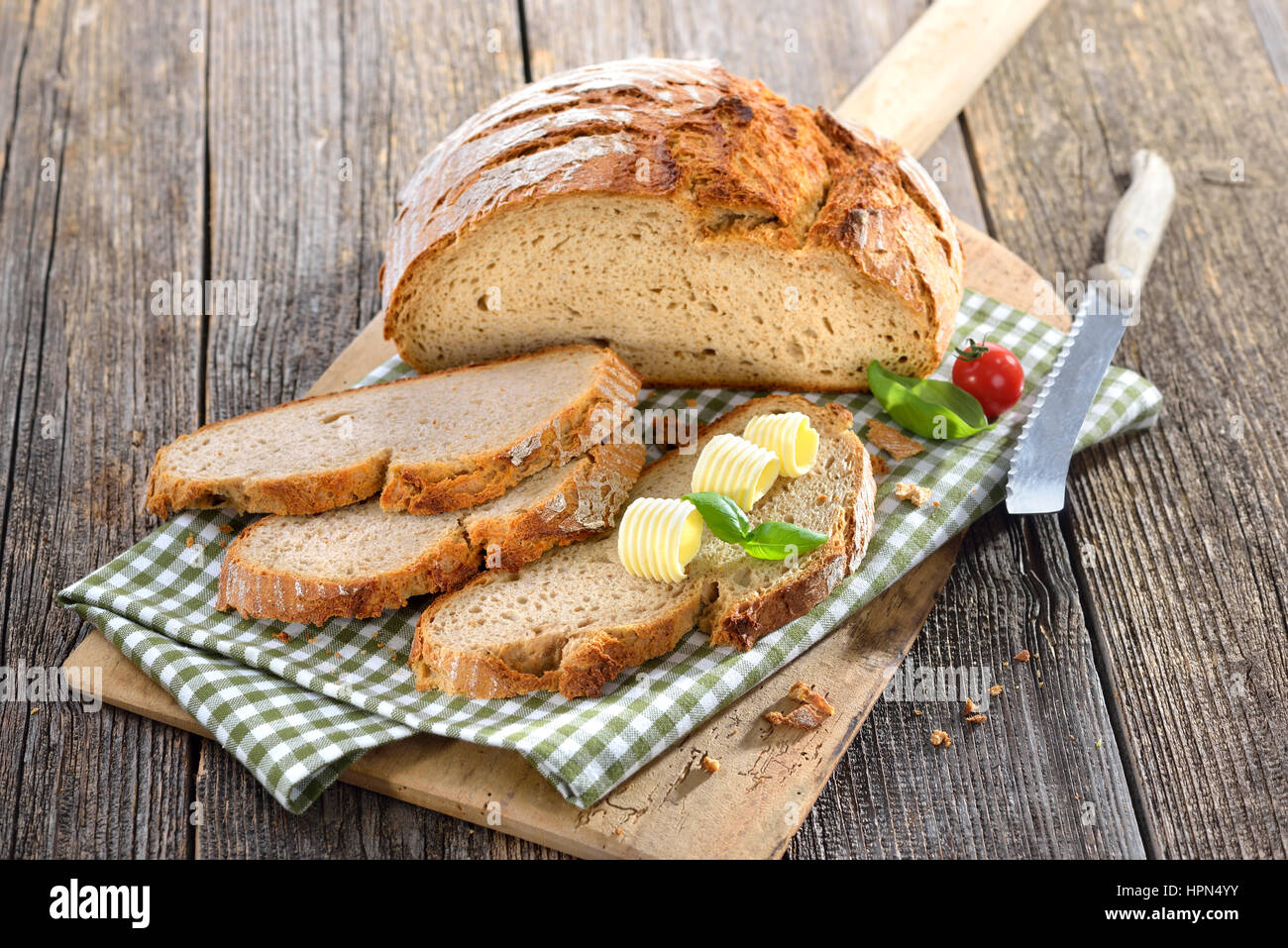 Fresh stone oven baked bread with butter rolls served on an old wooden baking board Stock Photo