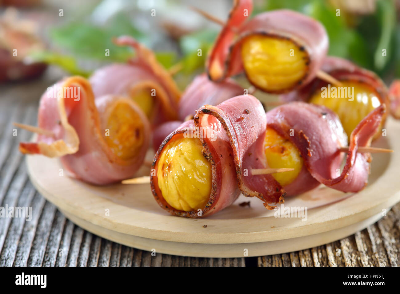 Roasted chestnuts wrapped in South Tyrolean bacon served on toothpicks for finger food Stock Photo