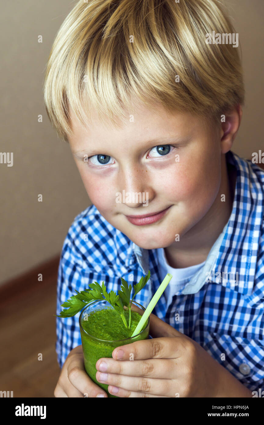 Child (boy) drinking healthy green vegetable smoothie healthy eating