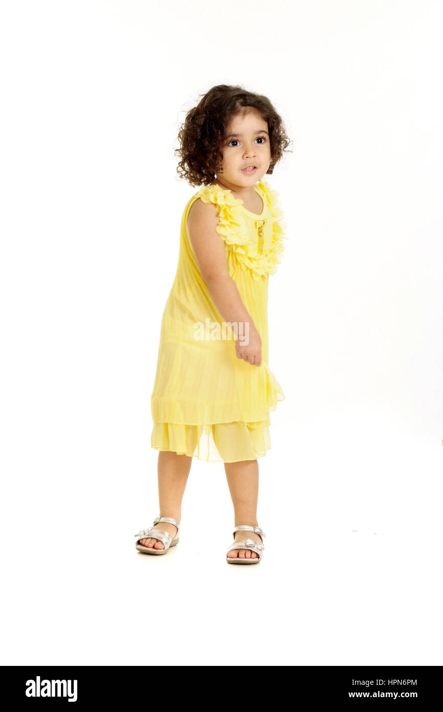 little girl in a yellow dress posing on a white background Stock Photo ...