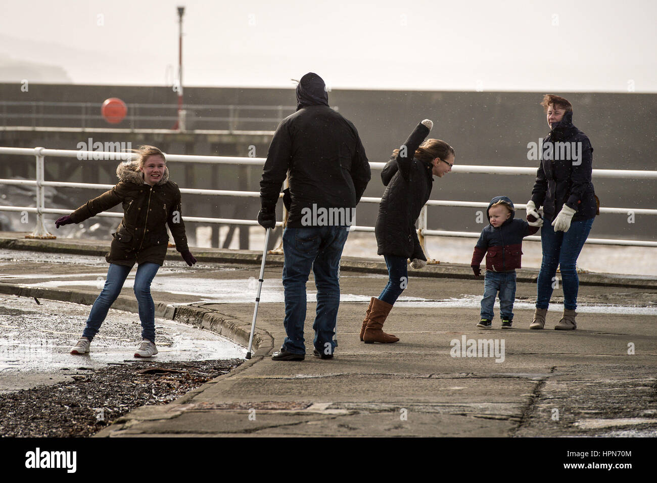 People are blown around by the wind while walking along the sea front in Aberystwyth, Wales, as flights have been cancelled and commuters were warned they faced delays after Storm Doris reached nearly 90mph on its way to batter Britain. Stock Photo