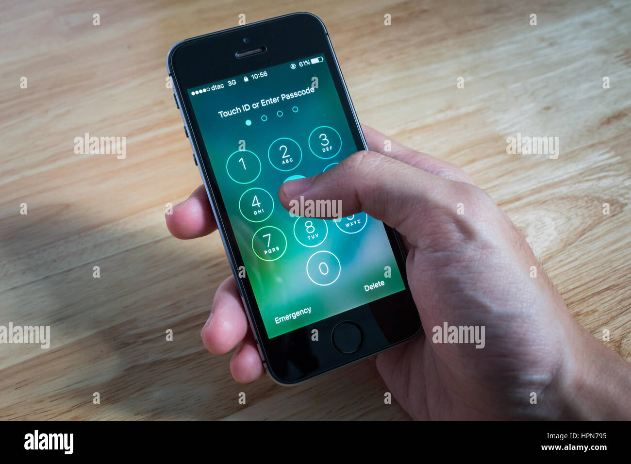 Bangkok, Thailand - February 22, 2017 : Apple iPhone5s held in one hand showing its screen with numpad for entering the passcode. Stock Photo