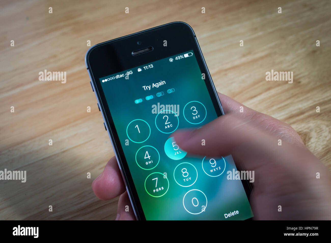 Bangkok, Thailand - February 22, 2017 : Apple iPhone5s held in one hand showing its screen with numpad for entering the passcode. Stock Photo