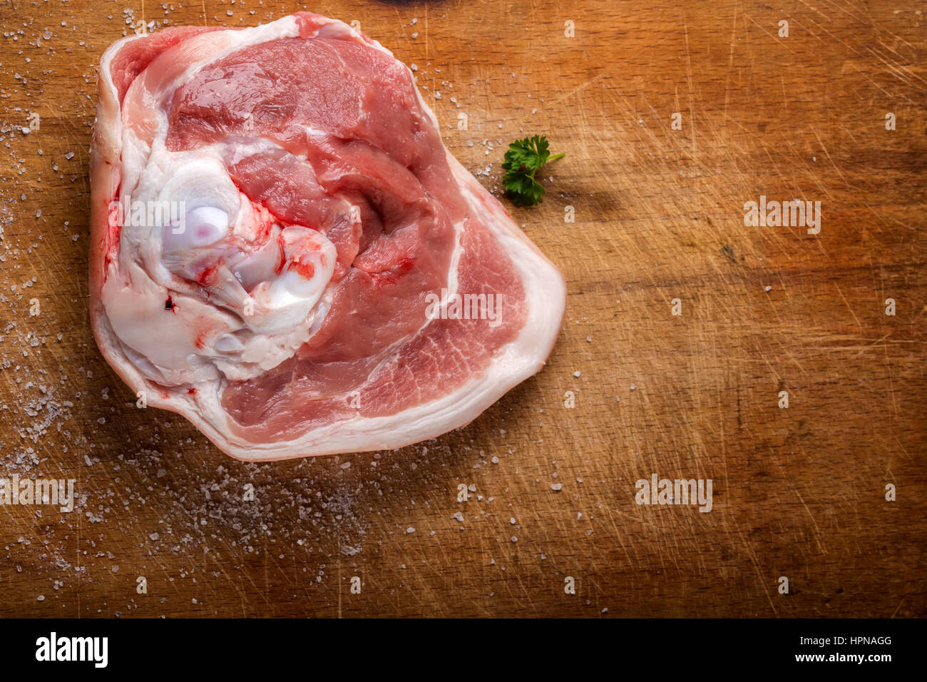 One piece of raw pork with salt and parsley on wood with copy space Stock Photo