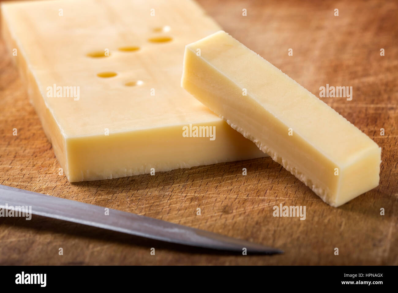 Emmental cheese with knife on wooden cutting board Stock Photo