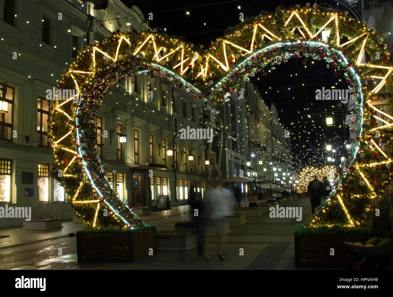 View of street decorations with colourful lights made with colourful flowers in city center of Moscow for Christmas and New Year Eve. People walk unde Stock Photo