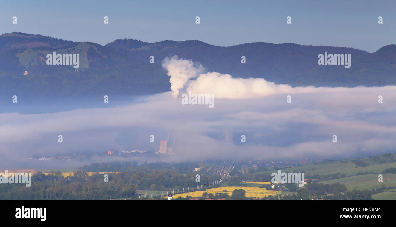 Factory pollutes clean air in mountains smoke coming from tube Stock Photo