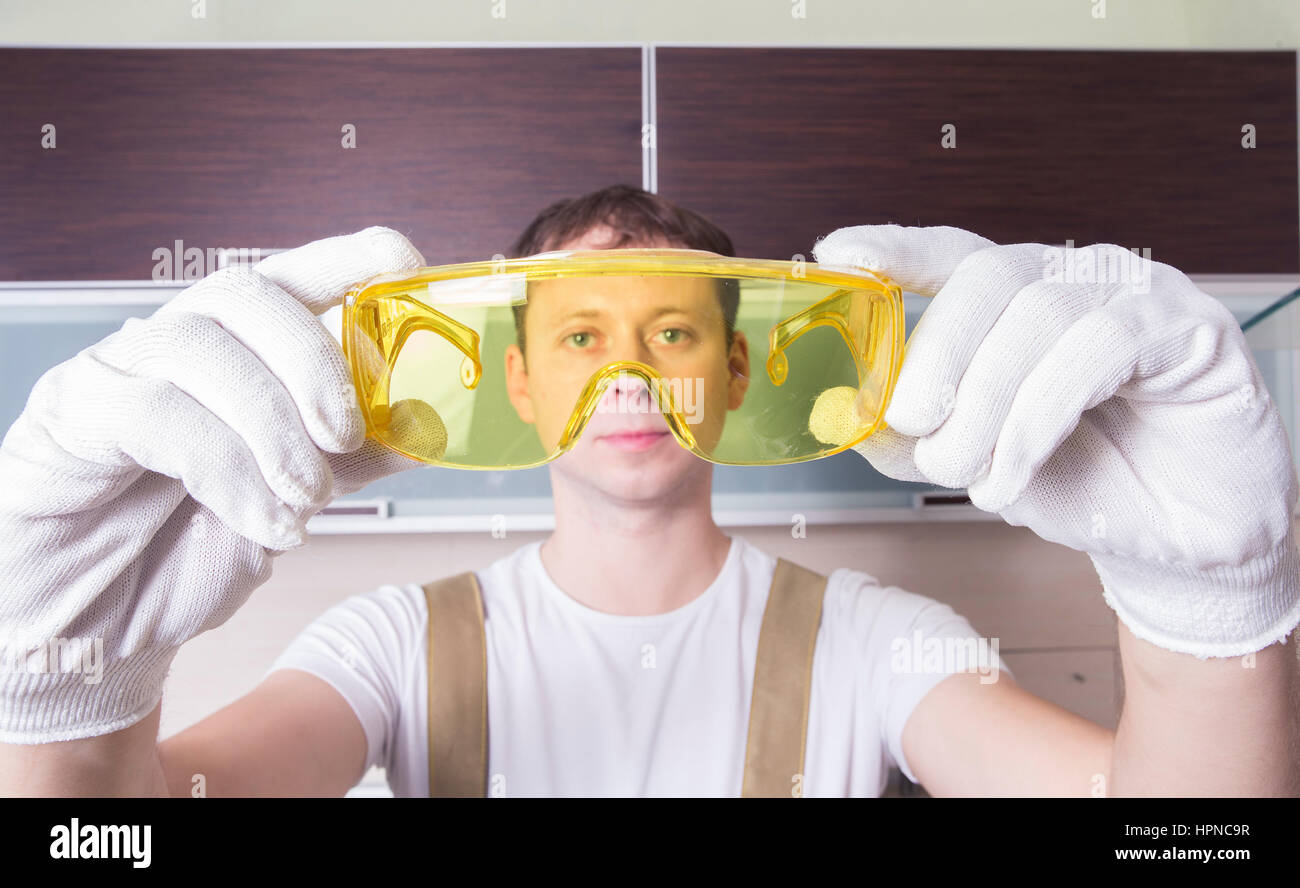 Man hold yellow safety glasses. Worker in work uiform. Stock Photo