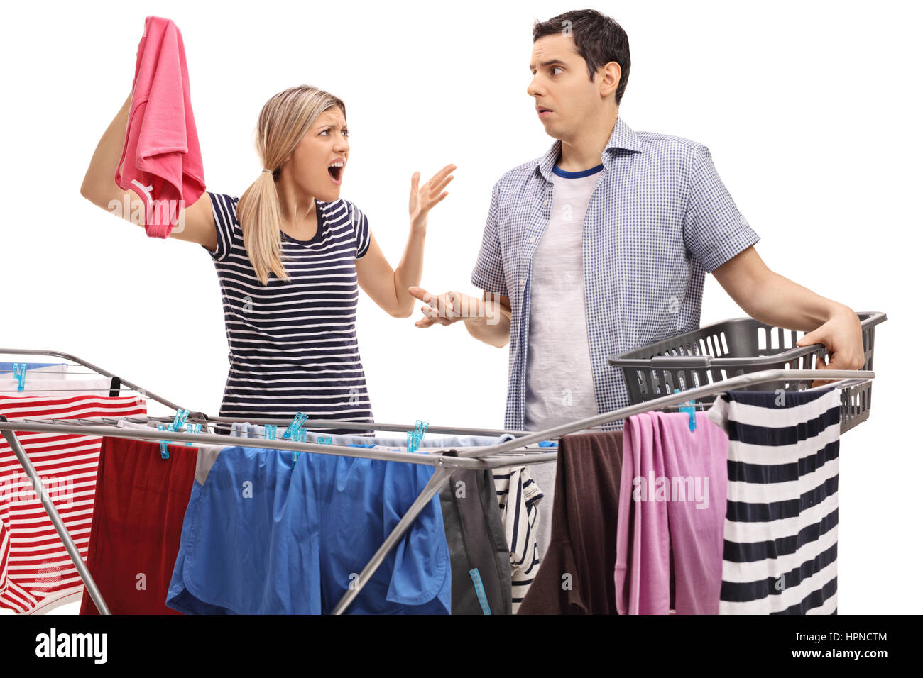 Young couple having an argument while hanging clothes on a clothing rack dryer isolated on white background Stock Photo