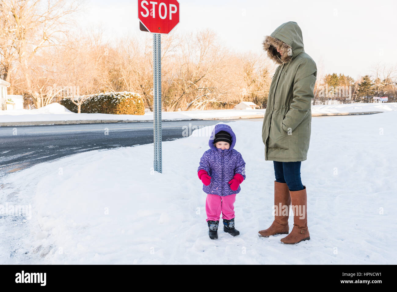 Mother and toddler all rugged up in sub-zero temperatures outdoors in Canada at bus stop Stock Photo