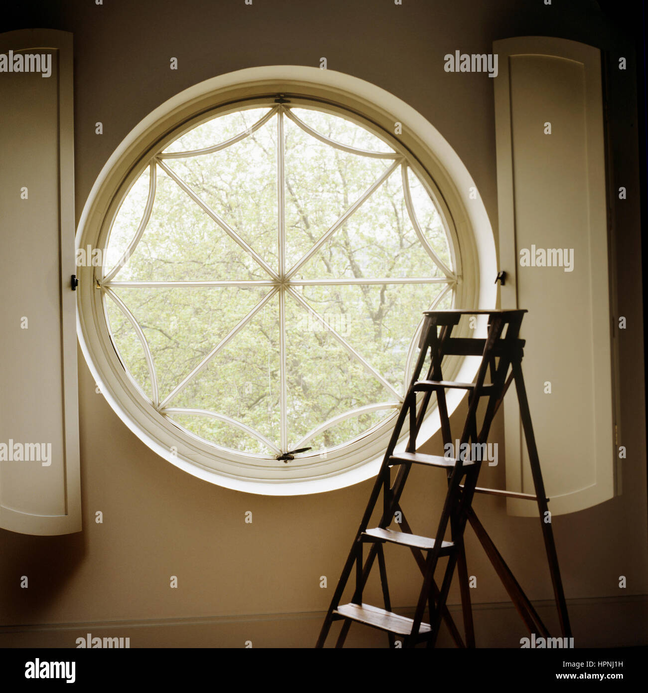 Step ladder at large round window Stock Photo