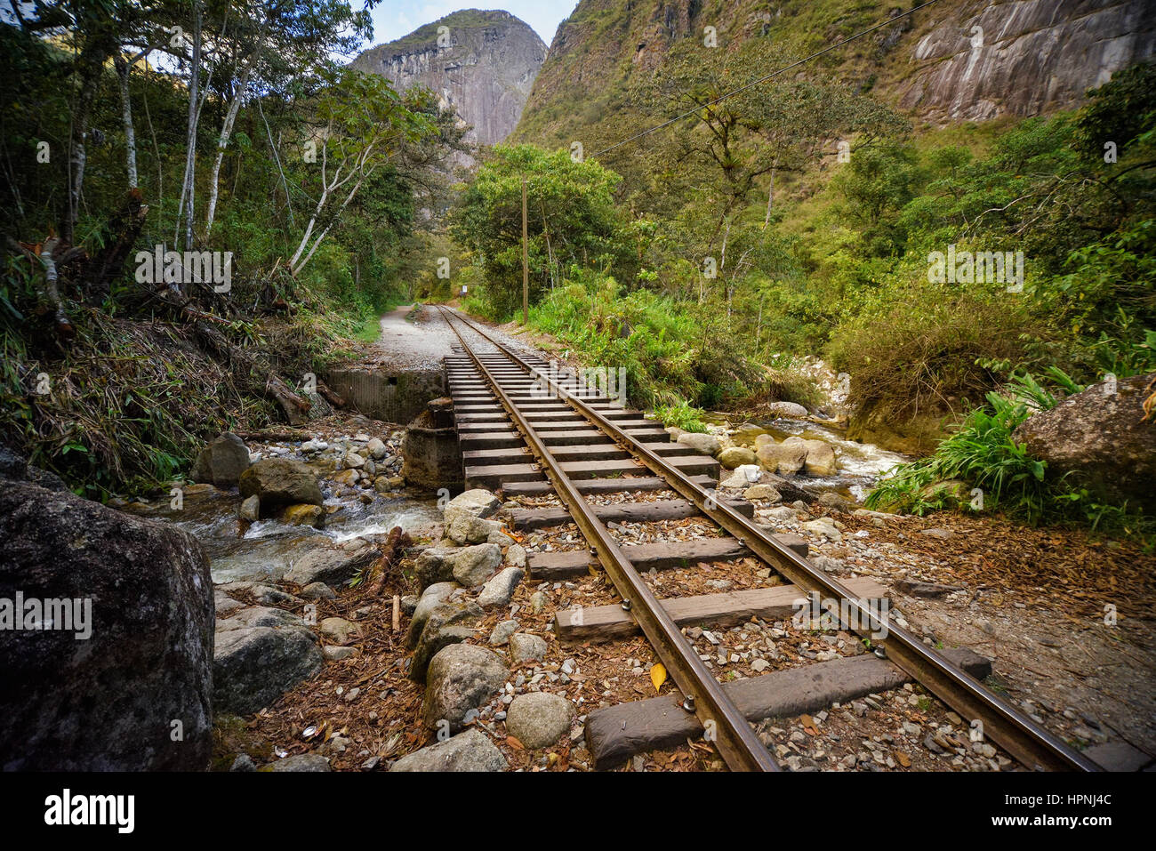 Railway track crossing jungle and Urubamba river, connecting Machu Picchu village to hydroelectric station, mostly used for tourism and cargo purpose. Stock Photo