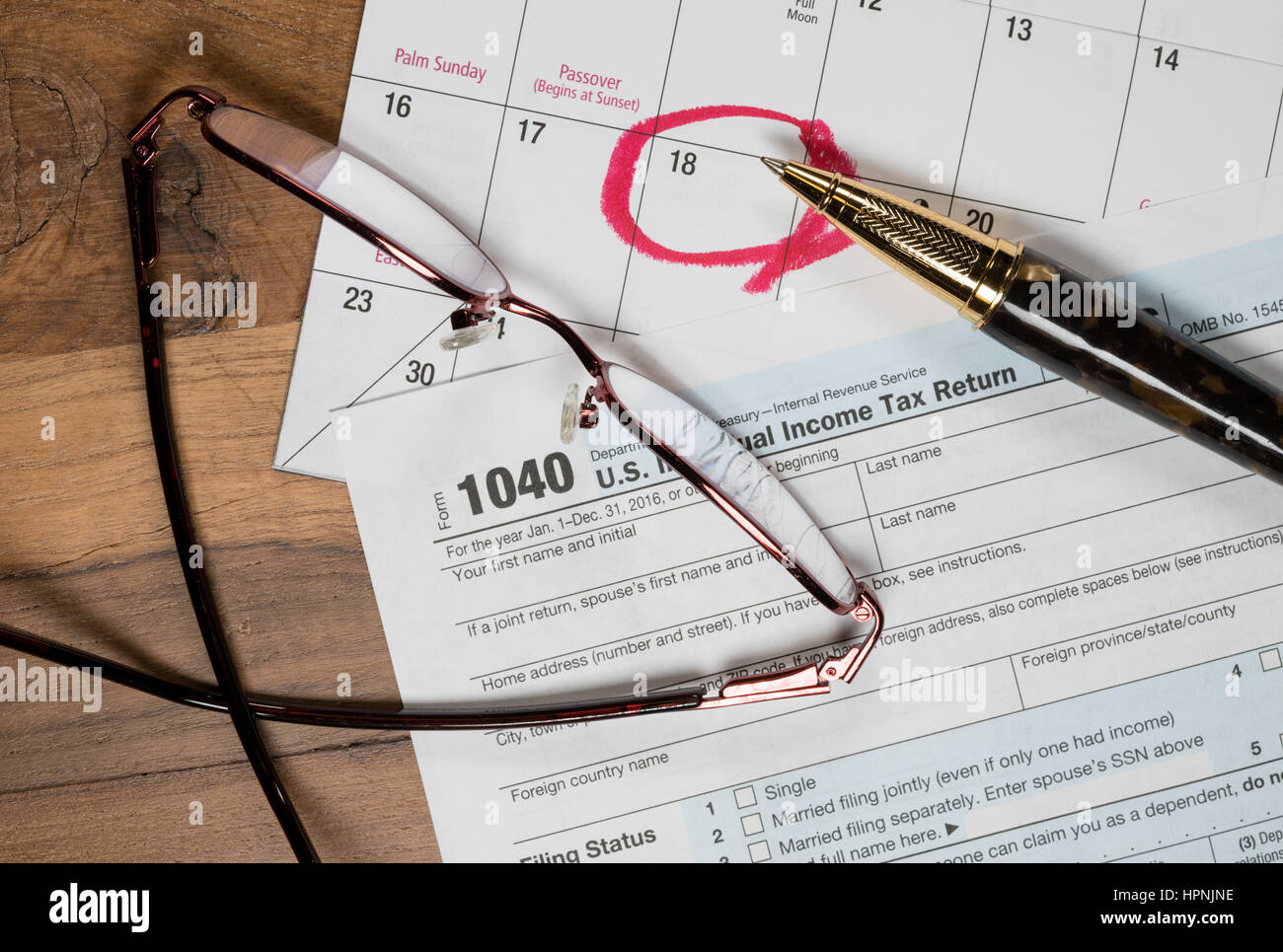 Calendar on top of form 1040 income tax form for 2016 showing tax day for filing is April 18 2017 Stock Photo