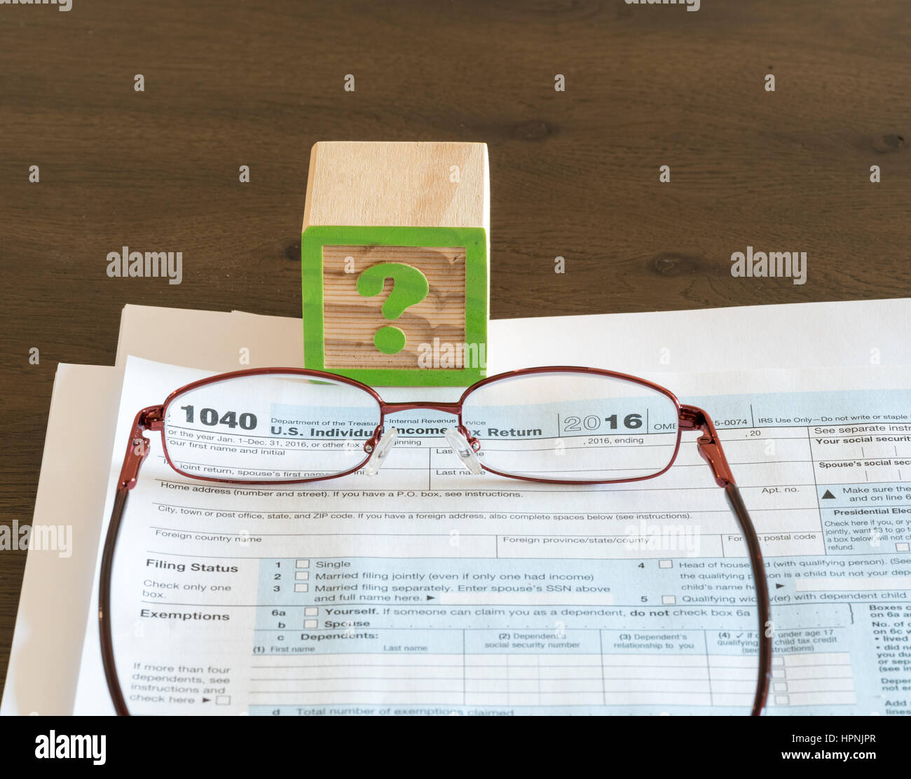 Question mark wooden block illustrating problems or issues in completing US IRS tax form Stock Photo