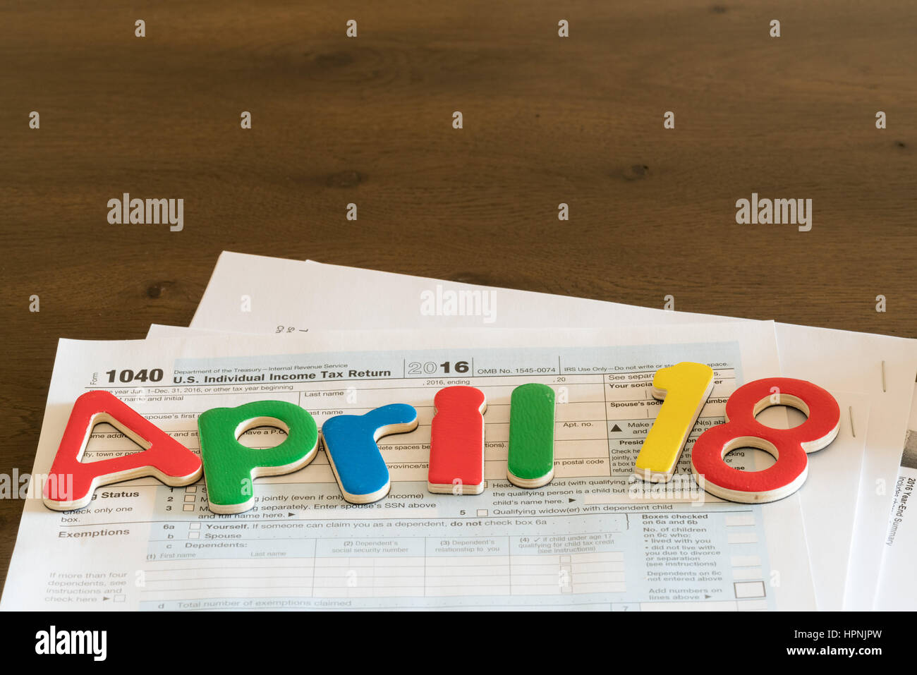 Wooden letters on top of 1040 income tax form for 2016 showing tax day for filing is April 18 2017 Stock Photo