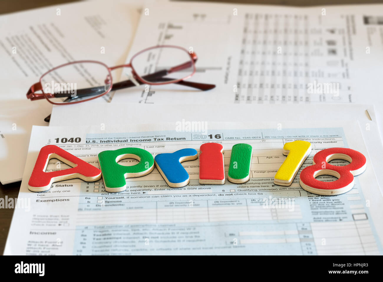 Wooden letters on top of 1040 income tax form for 2016 showing tax day for filing is April 18 2017 Stock Photo