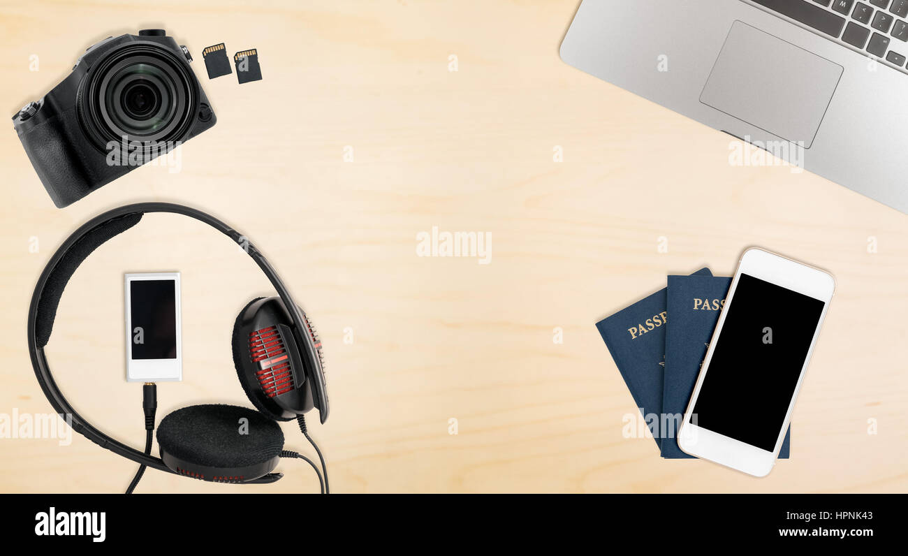 Clean and tidy wooden desk with equipment ready for travel including camera, laptop, phone, music player and passports Stock Photo