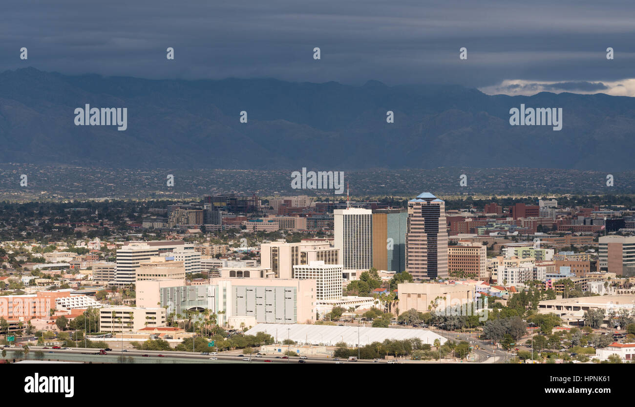 Downtown area of Tucson in Arizona with the sun lighting the buildings while storm clouds gather over distant mountain range Stock Photo