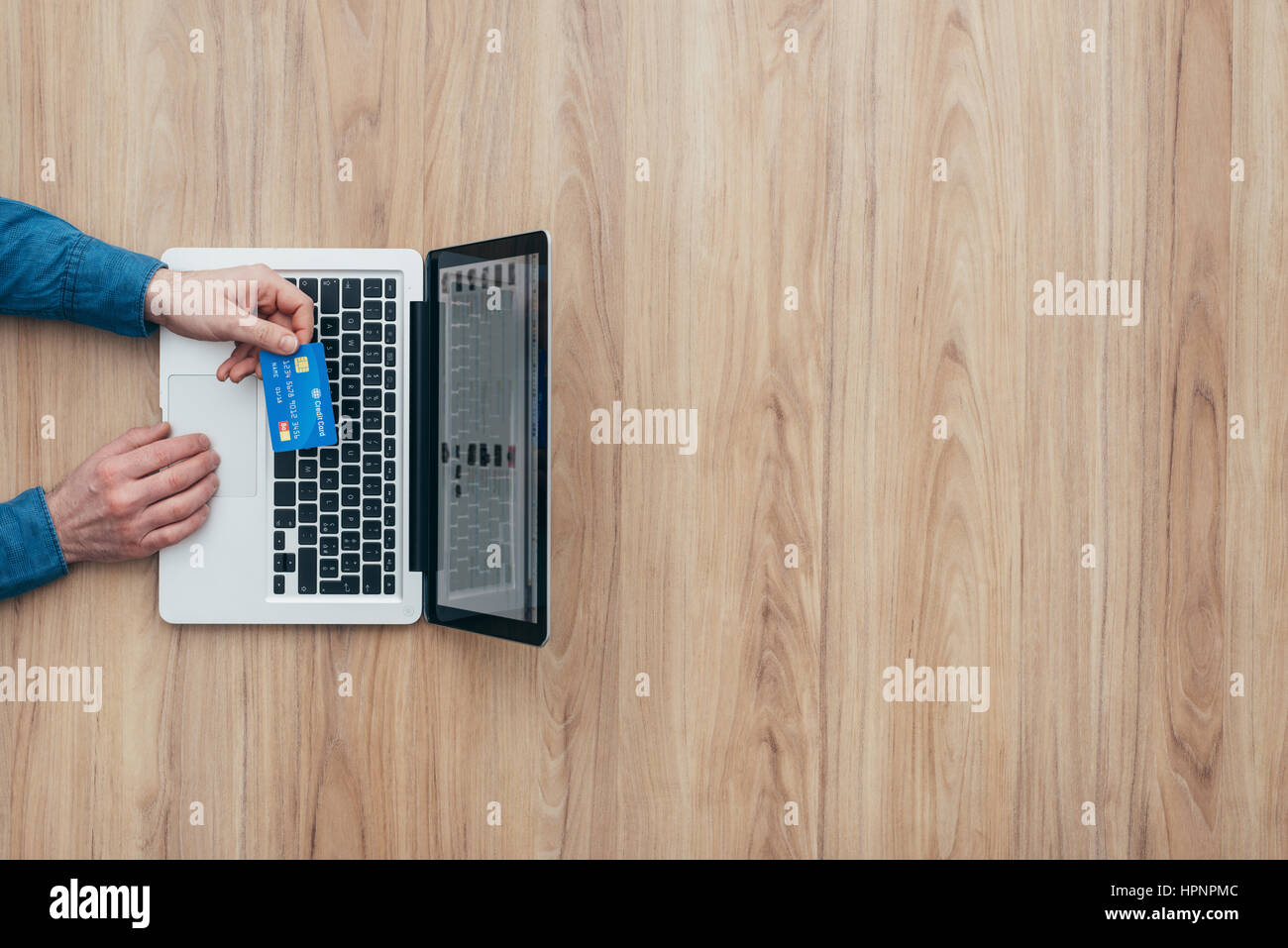 Man working at desk and purchasing products online, he is making a payment using a credit card, online shopping concept Stock Photo