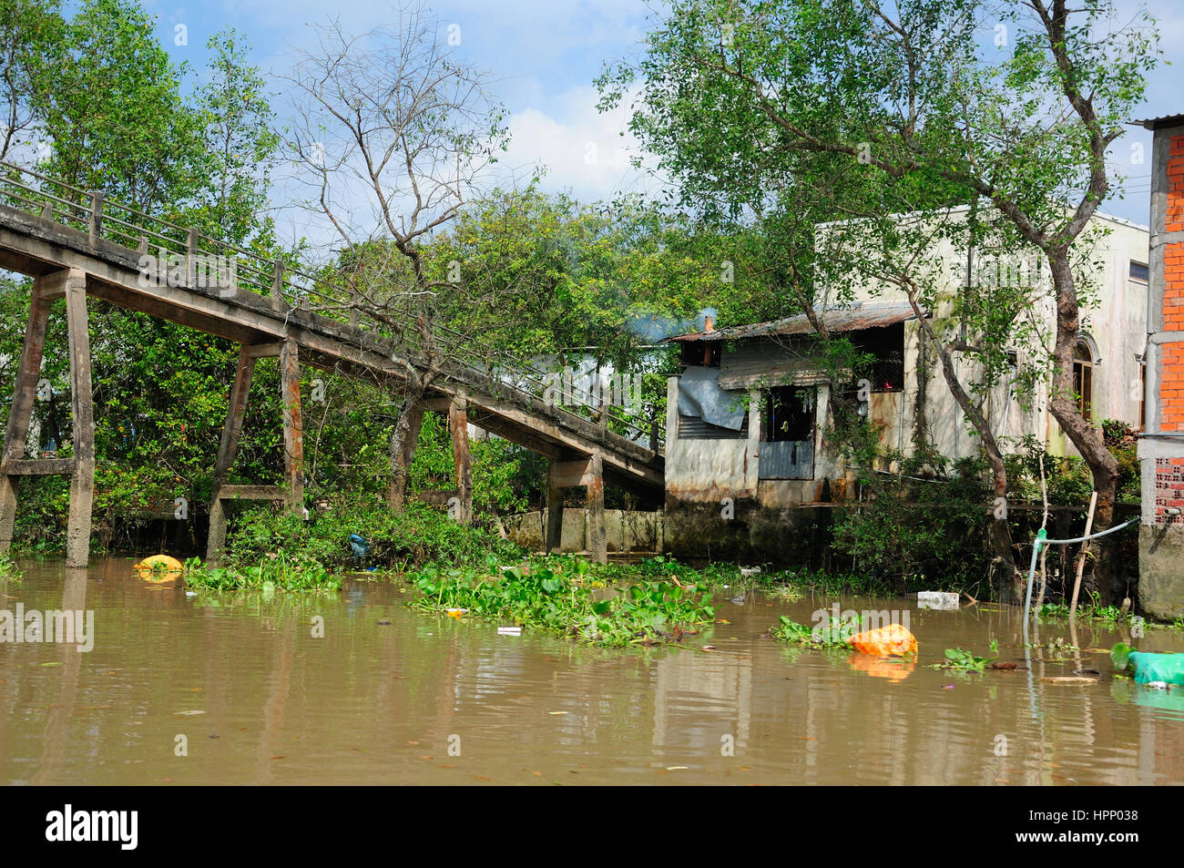 A weathered bridge and buildings within the Mekong River delta in South vietnam in near the town of Vinh Long. Stock Photo