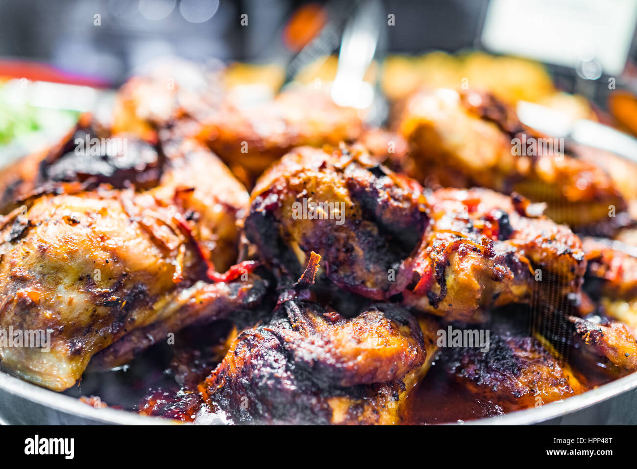 Roasted chicken thighs on display with charred skin and peppers Stock
