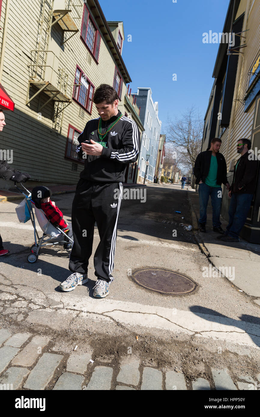 Young man wearing a black Adidas sweatsuit while looking at the phone Stock Photo