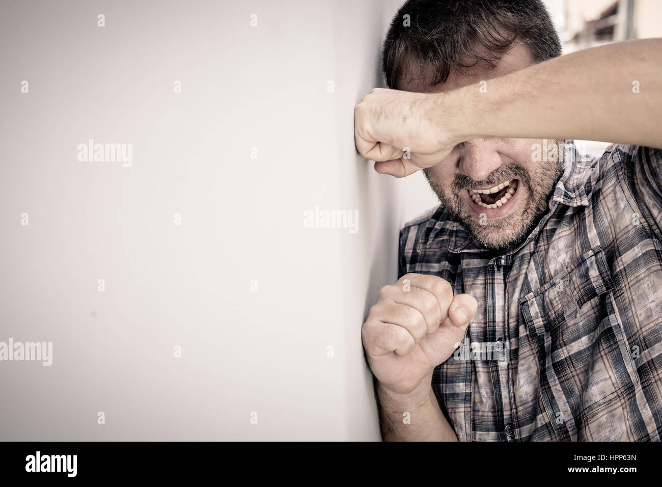 portrait one sad man standing near a wall and covers his face at the ...