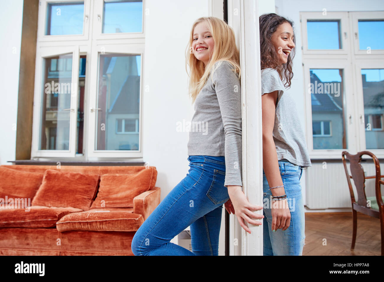 Two happy girls standing  on opposite sides of a door Stock Photo